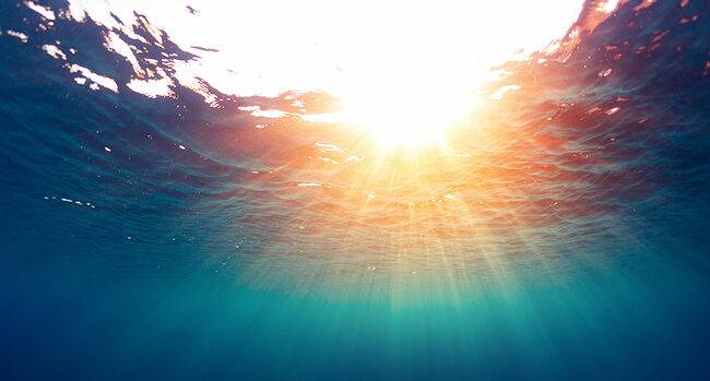 View of sunlight coming down through calm water, as seen from below the surface. Stress matters, and every step we can take to calm the waters will help our overall well-being.